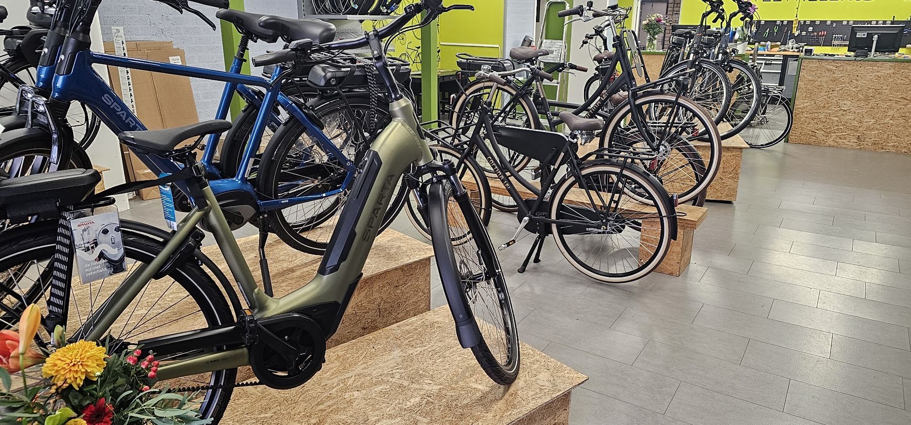Elektrische fietsen in groen, blauw en zwart opgesteld in de winkel