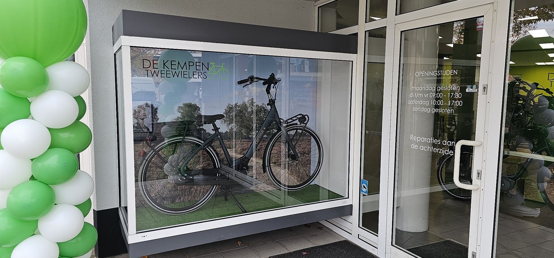 Etalage van De Kempen Tweewielers met het logo op het glas en een Cortina e-bike